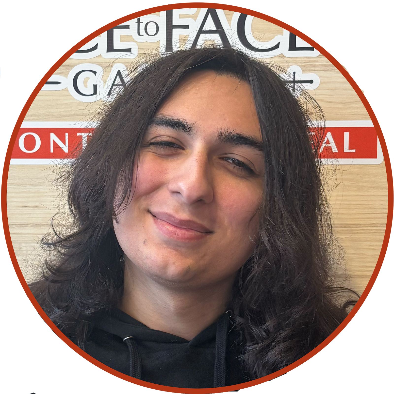 Alex Sowa, smiling at the camera in front of the Face to Face Games sign and logo